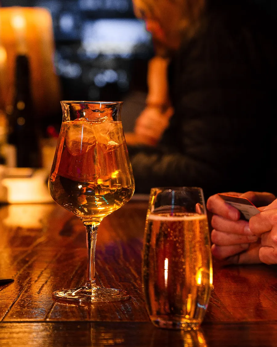 A tulip glass of something golden and a pint on the bar.